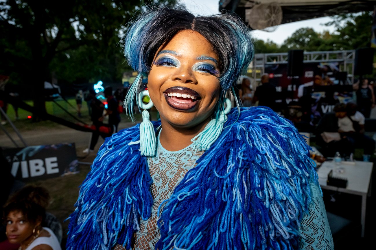 Portrait of smiling Black female Afropunk audience member dressed in blue yarn shirt