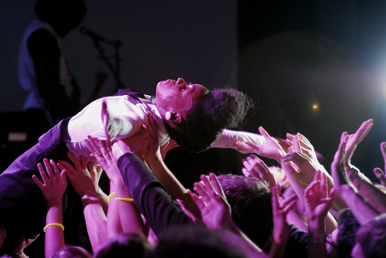 Side view of artist Janelle Monáe crowd surfing atop audience