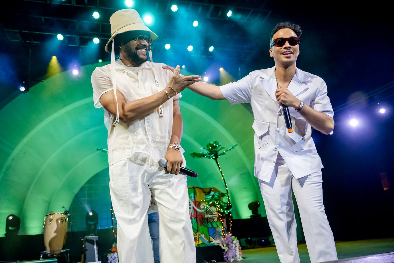 Artists Maxwell and Michaël Brun smiling while performing on green lit stage