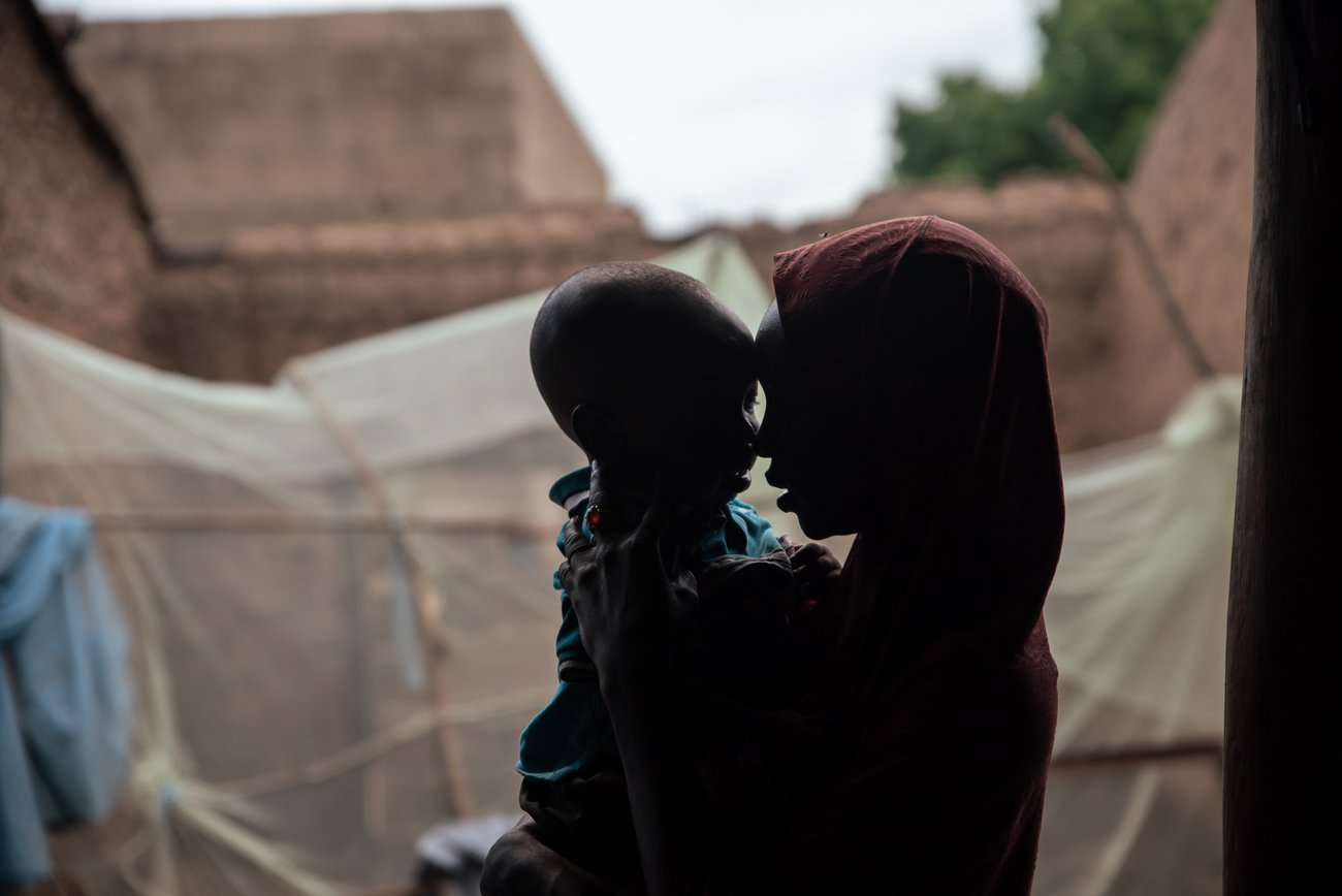 Side view silhouette of Black woman in headscarf holding child to her face