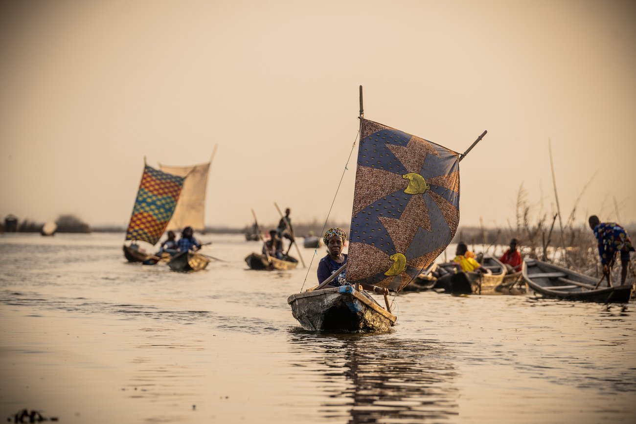 Group of African people in small boats rowing in shallow water