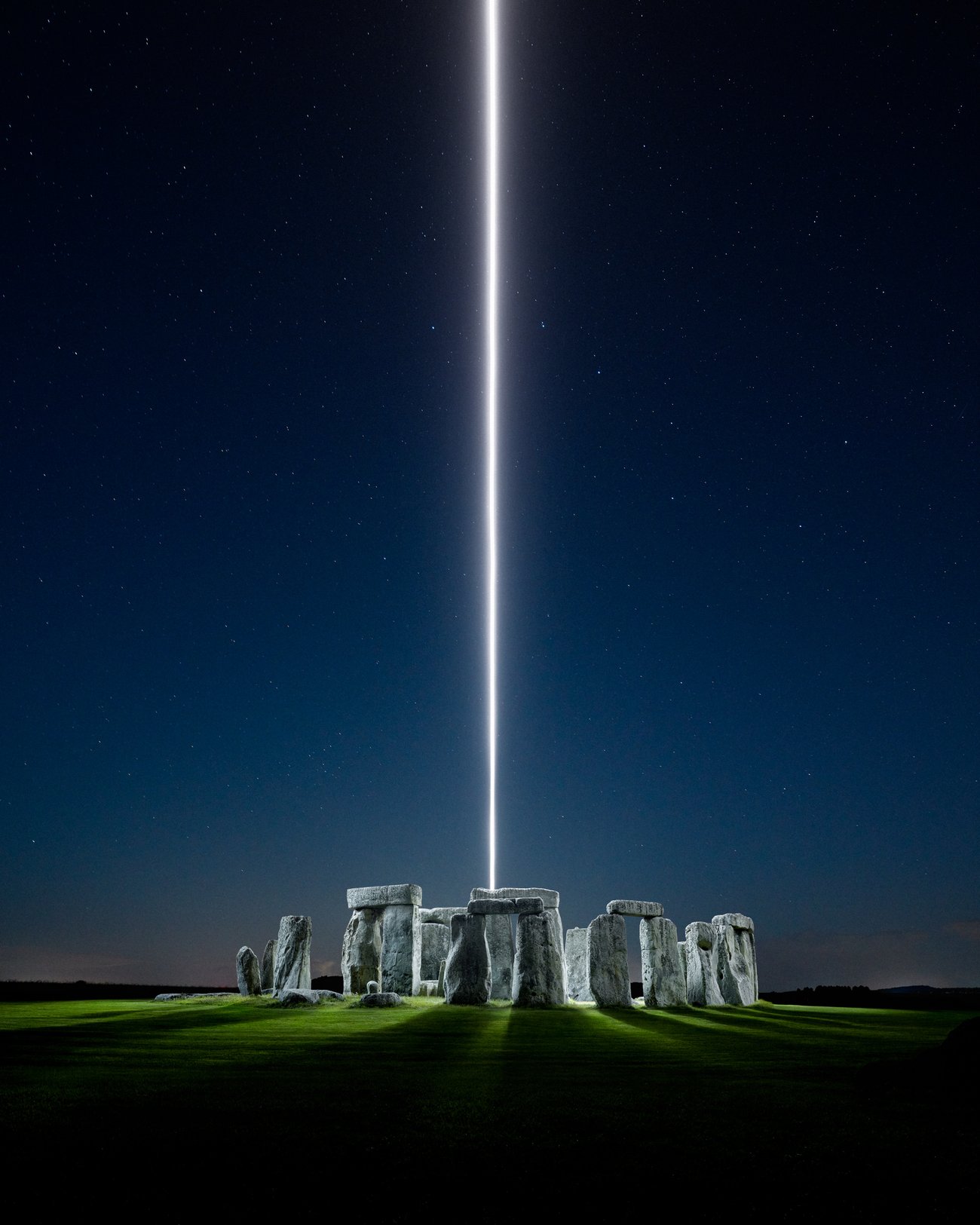 Thin, singular stream of light emitting from the center of Stone Henge, UK at night
