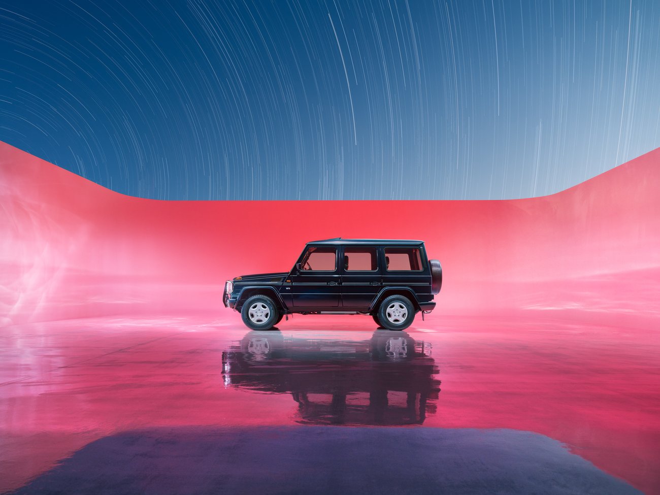 Side view of black 4x4 vehicle in a pink space with no roof and a blue sky with streaming lights