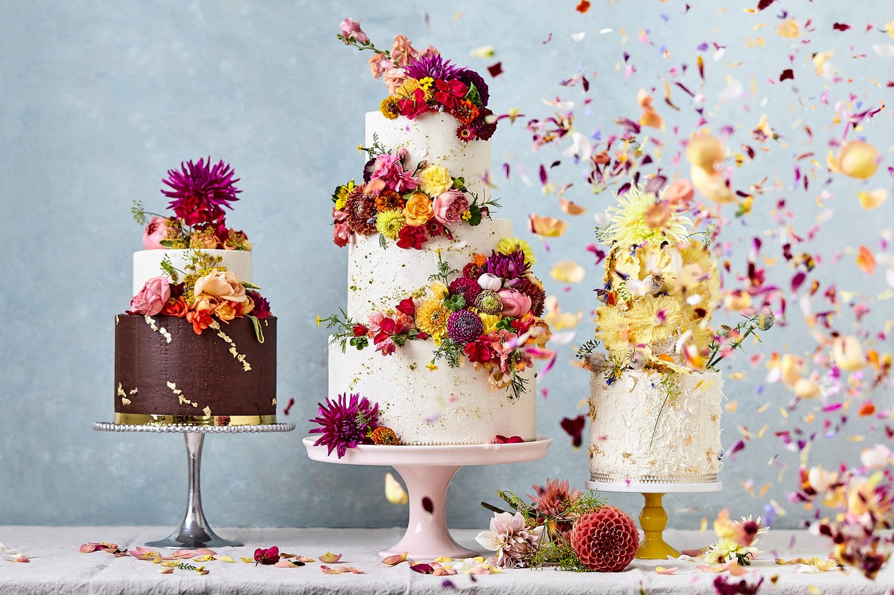 Three, three tiered cakes with floral decorations and petal confetti