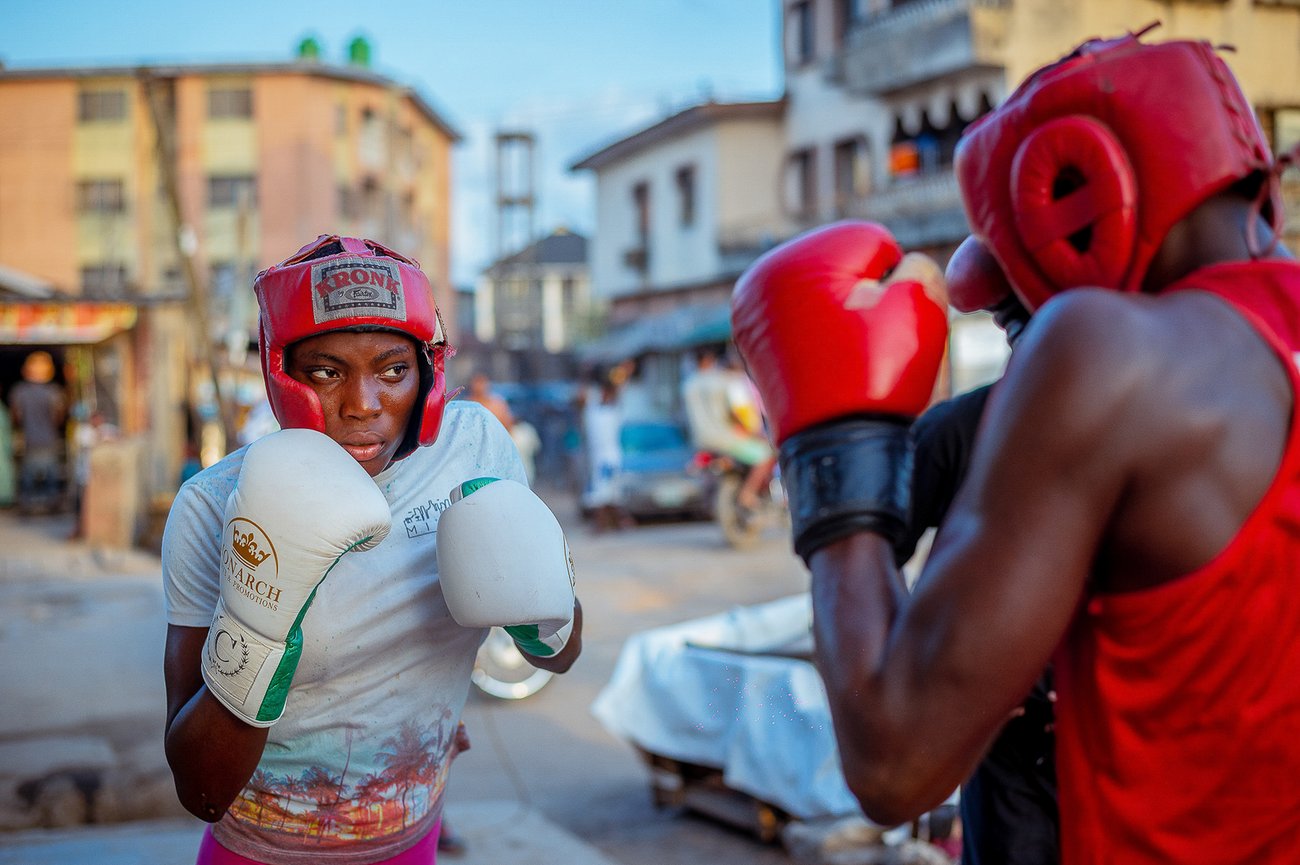 Black female boxing outside in red head guard